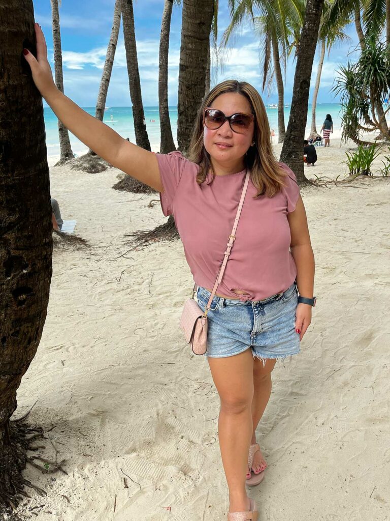 Une femme posant à côté d'un palmier à Boracay aux Philippines
