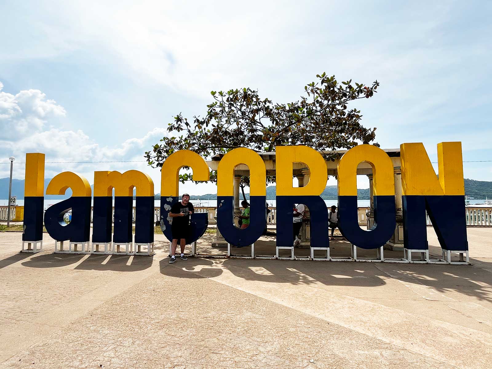 Un homme posant devant le logo Coron Philippines