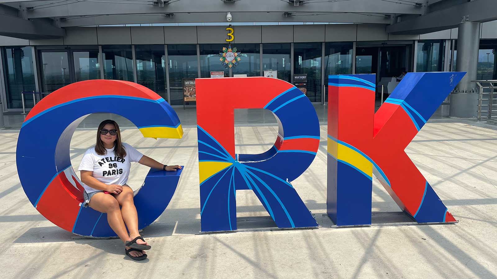 combien de temps pour aller aux philippines : une femme posant devant l'aéroport de Clarck