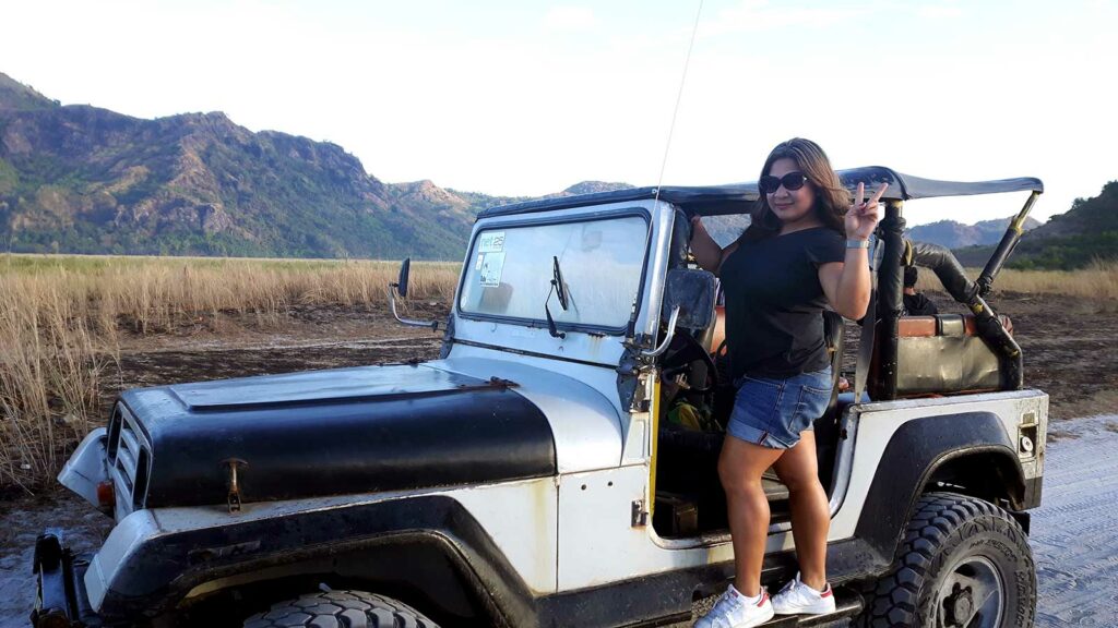 Une femme posant devant une jeep