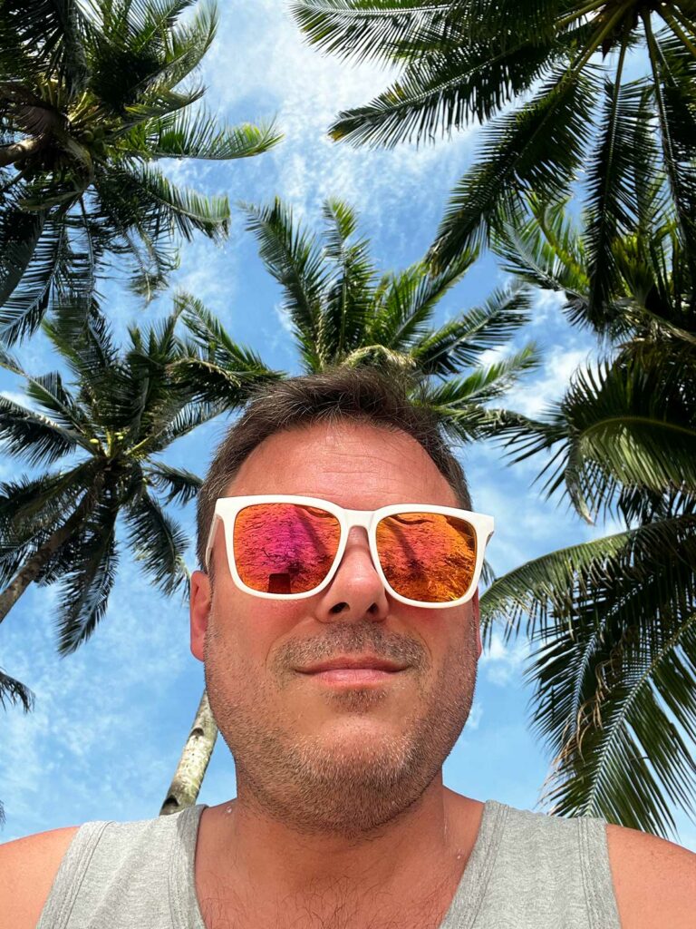quand partir aux philippines : un homme prenant un selfie devant des cocotiers