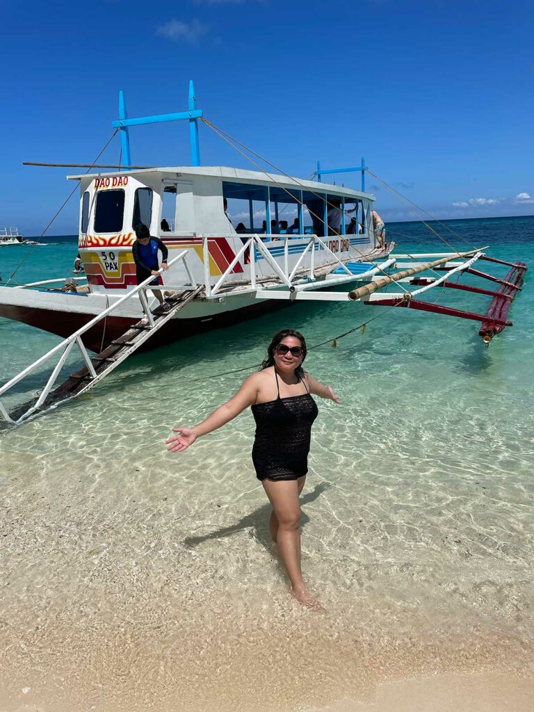 Visiter Boracay : une femme posant devant un bateau sur la plage